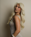 Woman with long blonde hair wearing a sparkly dress against a plain background