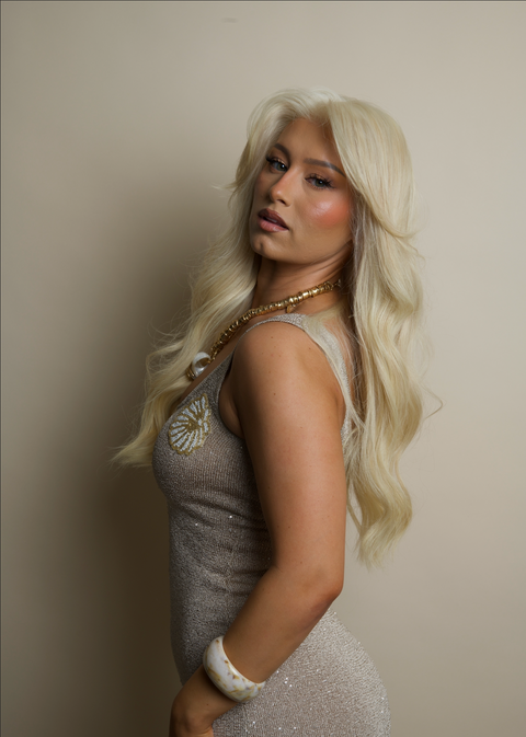 Woman with long blonde hair wearing a sparkly dress against a plain background