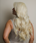 Person with long blonde hair wearing a sparkly dress against a plain background