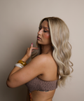 Woman with long blonde hair wearing a textured top against a neutral background