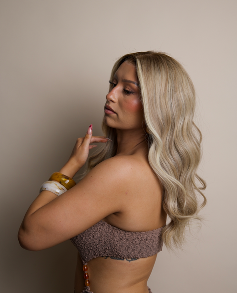 Woman with long blonde hair wearing a textured top against a neutral background