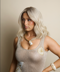 Woman wearing a sparkly top with shell designs against a beige background