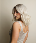 Woman with light-colored hair wearing a sparkly silver dress against a neutral background