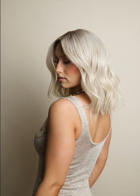 Woman with light-colored hair wearing a sparkly silver dress against a neutral background