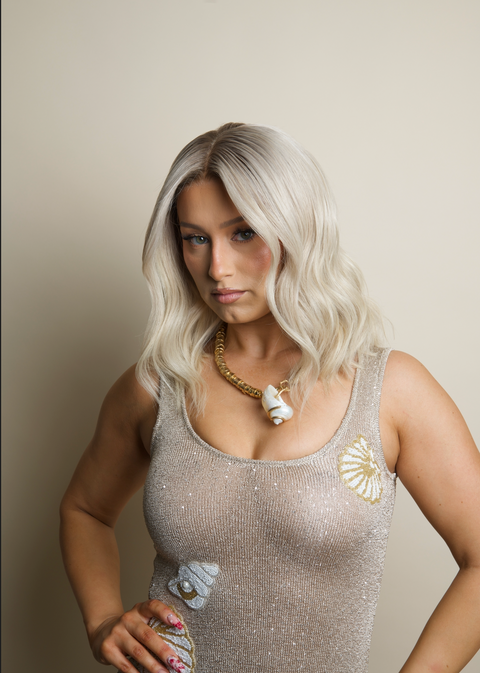Woman wearing a sparkly top with decorative elements against a plain background