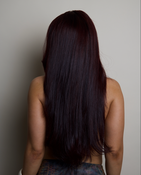 Person with long dark hair from behind against a plain background