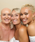 Three women with different hairstyles and skin tones smiling together against a beige background