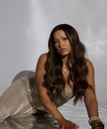 Woman in a sparkly dress lying on a white surface with a plain background