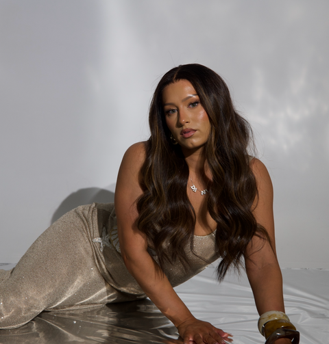 Woman in a sparkly dress lying on a white surface with a plain background