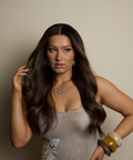 Woman with long dark hair wearing a sparkly dress against a neutral background