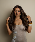 Woman with long dark hair wearing a sparkly dress against a beige background