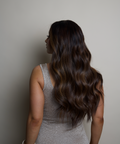 Woman with long, wavy hair wearing a silver dress against a neutral background